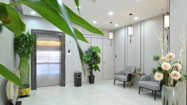 Eine moderne Lobby mit Empfangsschalter, Sitzgelegenheiten und einem Aufzug.