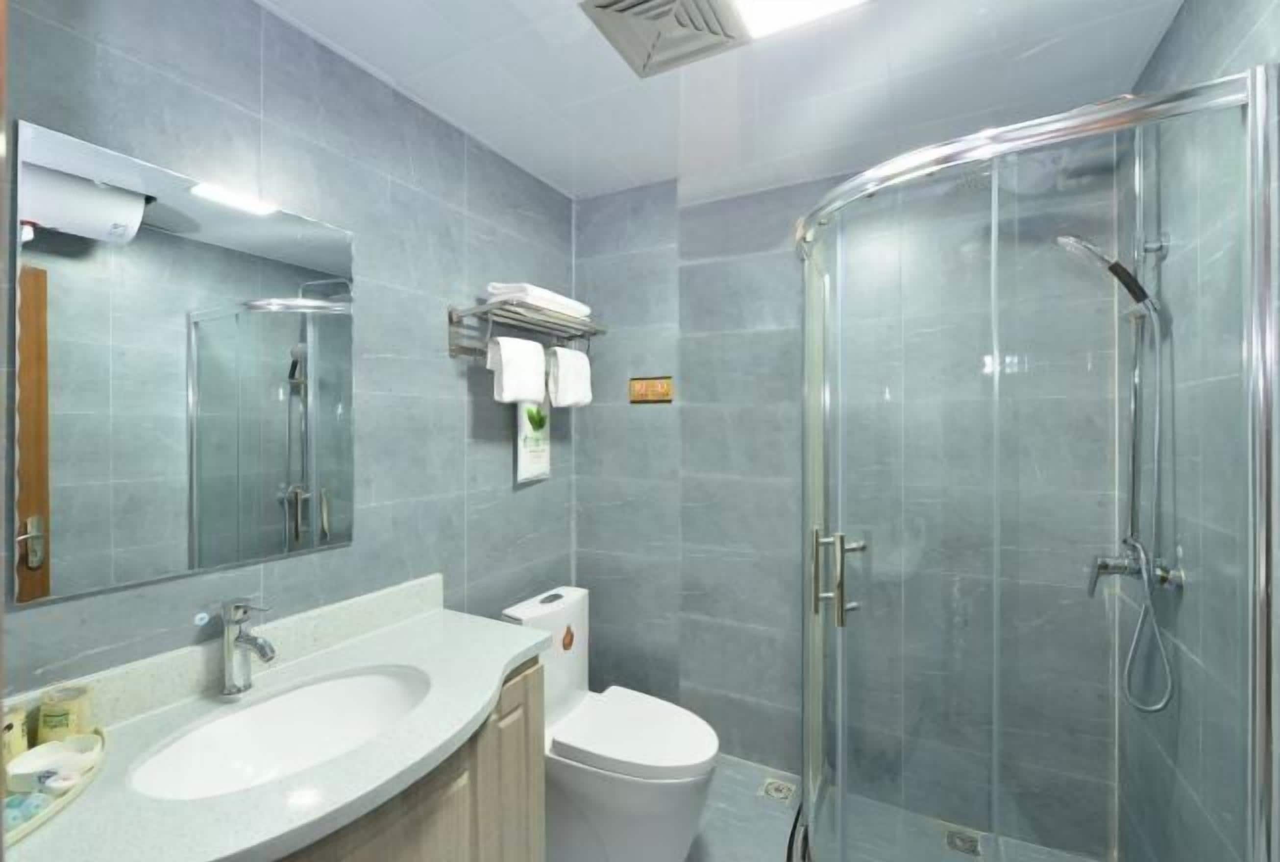 A modern bathroom with a glass shower enclosure, a sink, and a toilet.