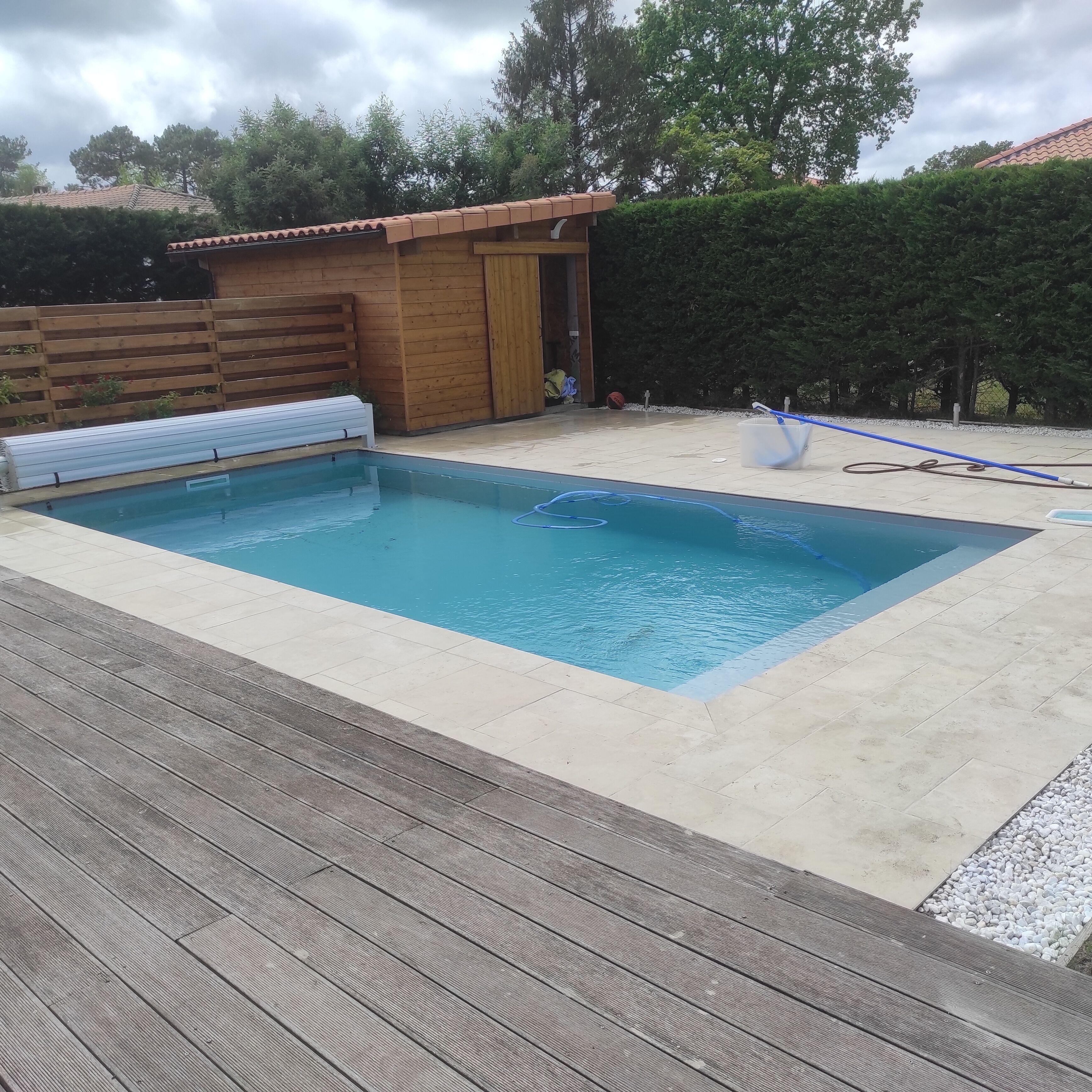 A rectangular swimming pool with a wooden deck surrounding it.