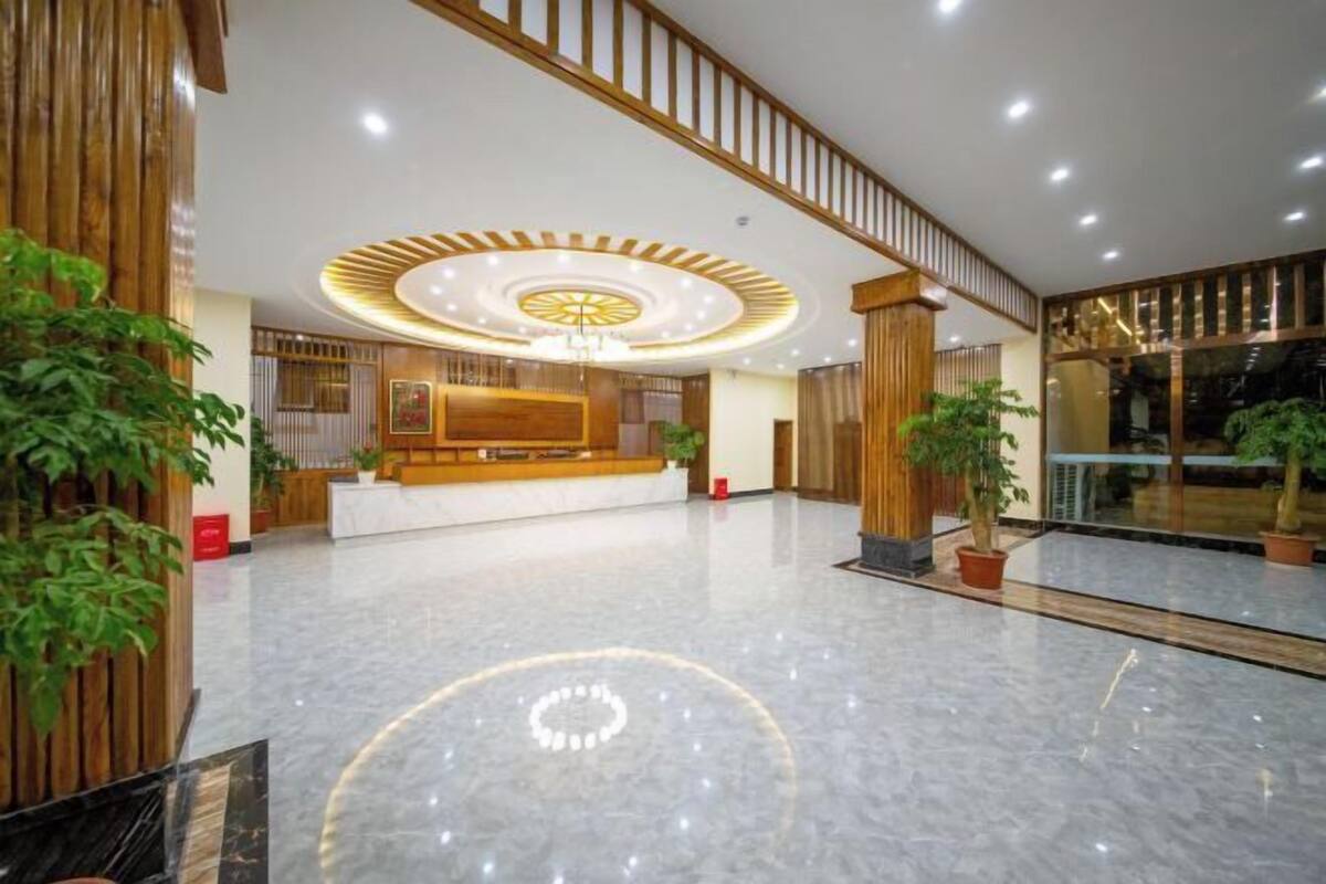Um hall amplo com balcão de recepção, detalhes em madeira e um lustre moderno.