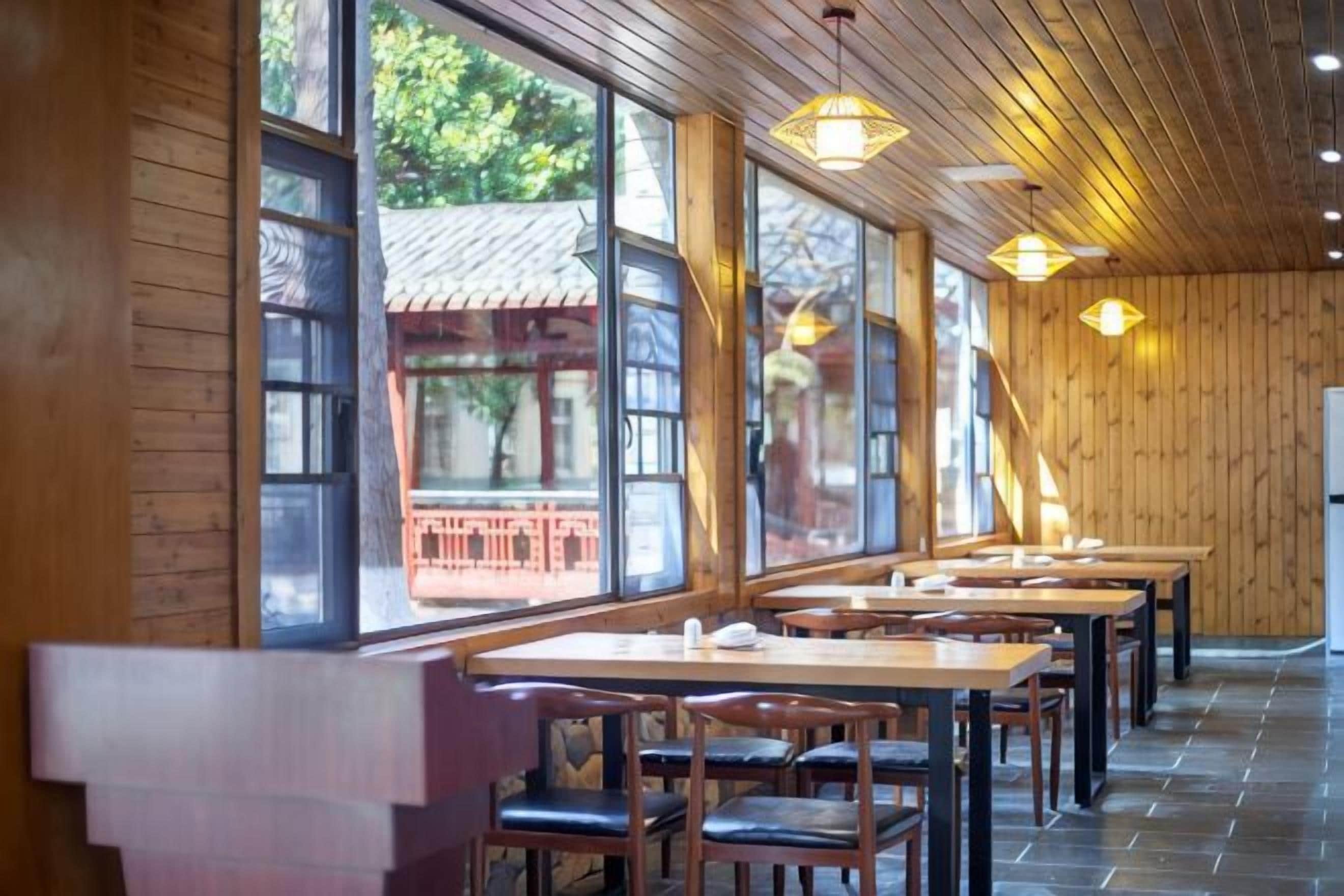 A restaurant with wooden walls and large windows, featuring tables and chairs.