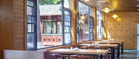 A restaurant with wooden walls and large windows, featuring tables and chairs.