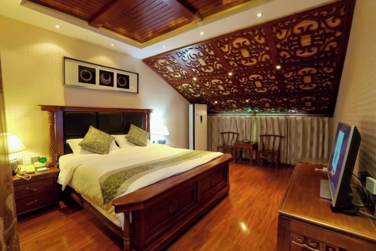 Une chambre à coucher avec un grand lit, une tête de lit en bois et un plafond décoratif.