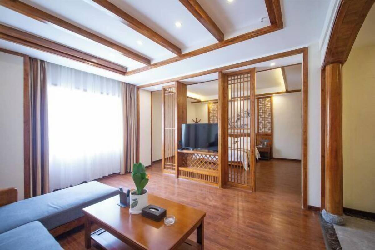 Quarto com sofá, mesa com planta, televisão e porta japonesa tradicional de correr.