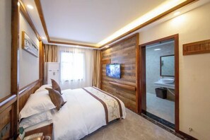 A hotel room with a bed, a television, a bathroom with a sink, and a sliding door. - Wulingyuan Hotel (Zhangjiajie)