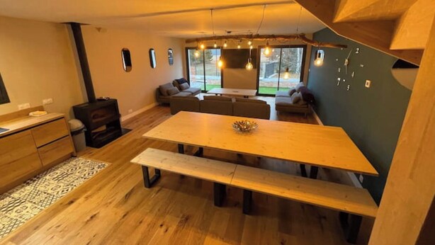 Un interior moderno con una mesa de comedor de madera, bancos y un conjunto de sofás.
