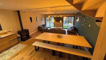 Een modern interieur met een houten eettafel, bankjes en een zithoek.