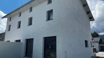 Un bâtiment moderne à deux étages, doté d’un toit plat, de grandes fenêtres et d’une petite pelouse verdoyante à l’avant.