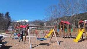 Un parque infantil con columpios y toboganes.