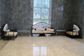 A modern lobby with a marble floor, a large window, and two sofas with cushions. - Yage Hotel (Napo)
