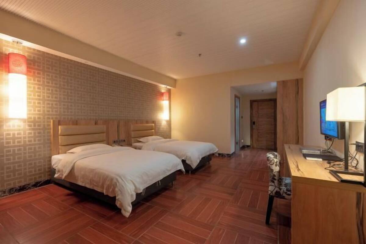 A hotel room with two beds, a desk with a computer, and a TV.