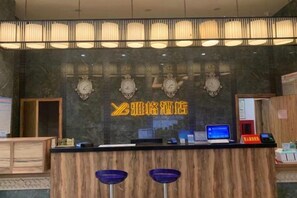 A reception desk with a digital screen, a clock, and a logo on the wall.