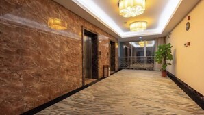 Ein Hotelgang mit Marmorwänden, einem gemusterten Boden und einer Topfpflanze.