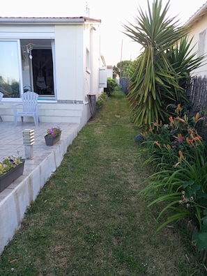 Een woonhuis met een terras, zitplaatsen buiten en een tuin.