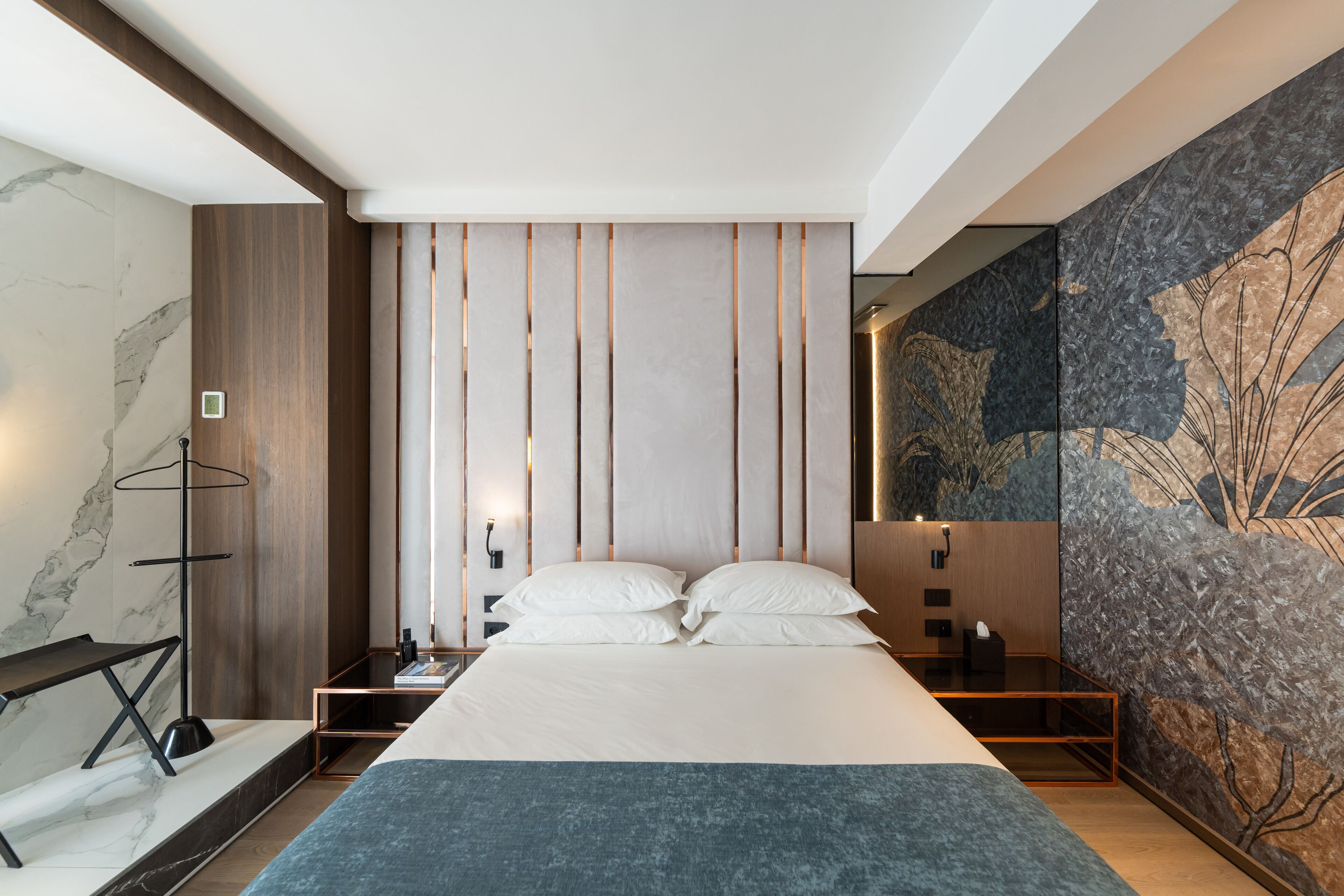 Une chambre moderne avec un grand lit, une table de chevet, un bureau et une étagère fixée au mur.
