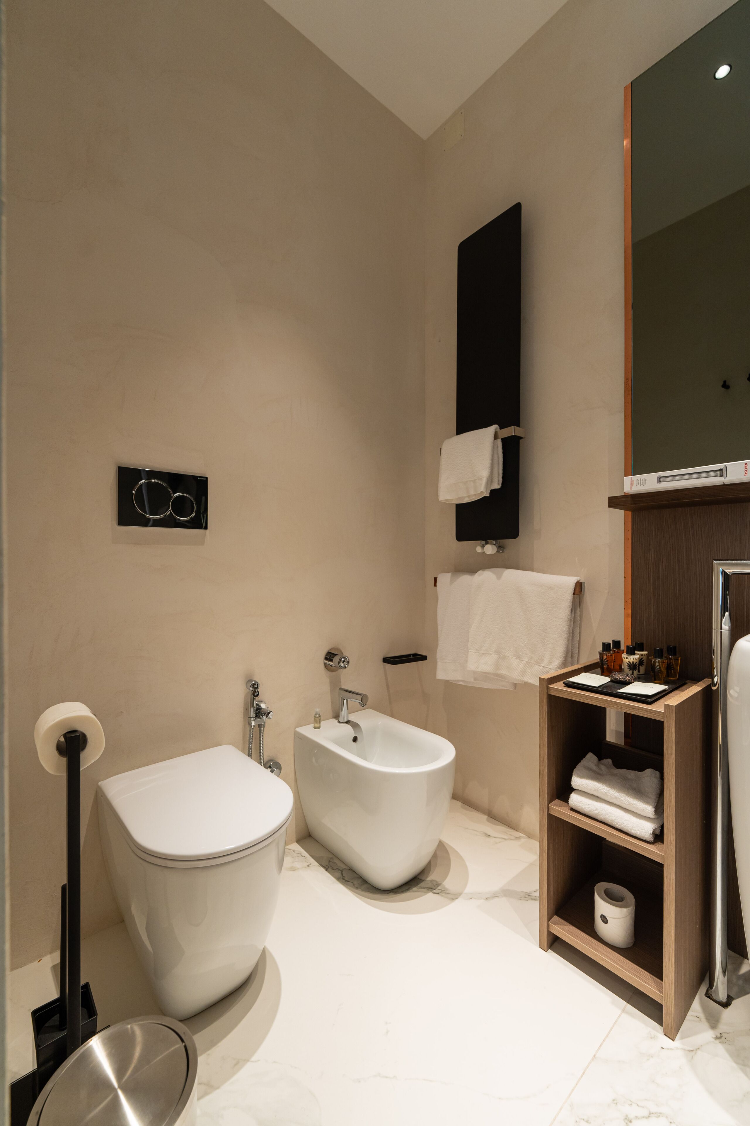 A modern bathroom with a bidet, toilet, and a vanity with a mirror.