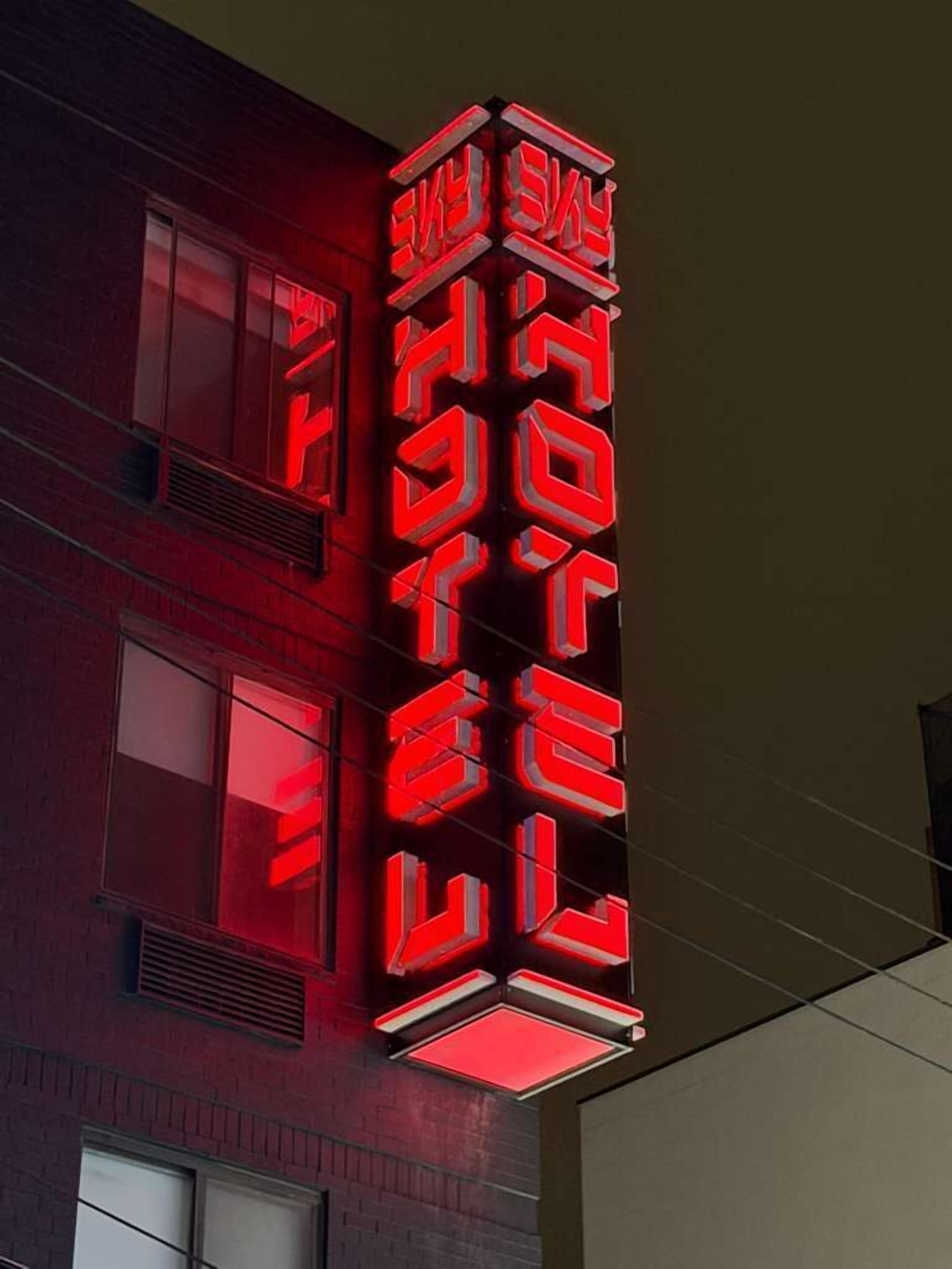A building with a vertical neon sign in red and white.