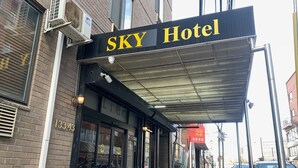 The exterior of SKY Hotel with a covered entrance, a brick facade, and a visible address number 13343. - Sky Hotel Flushing/LaGuardia Airport (Flushing)