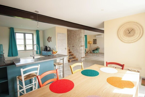 Un espace repas avec une table, des chaises et une cuisine en arrière-plan.