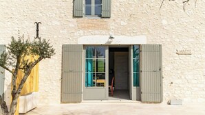 Ein rustikales Steinhaus mit Holztür und -läden, einem kleinen Fenster mit Läden und einem Schild mit der Aufschrift "HAITI".