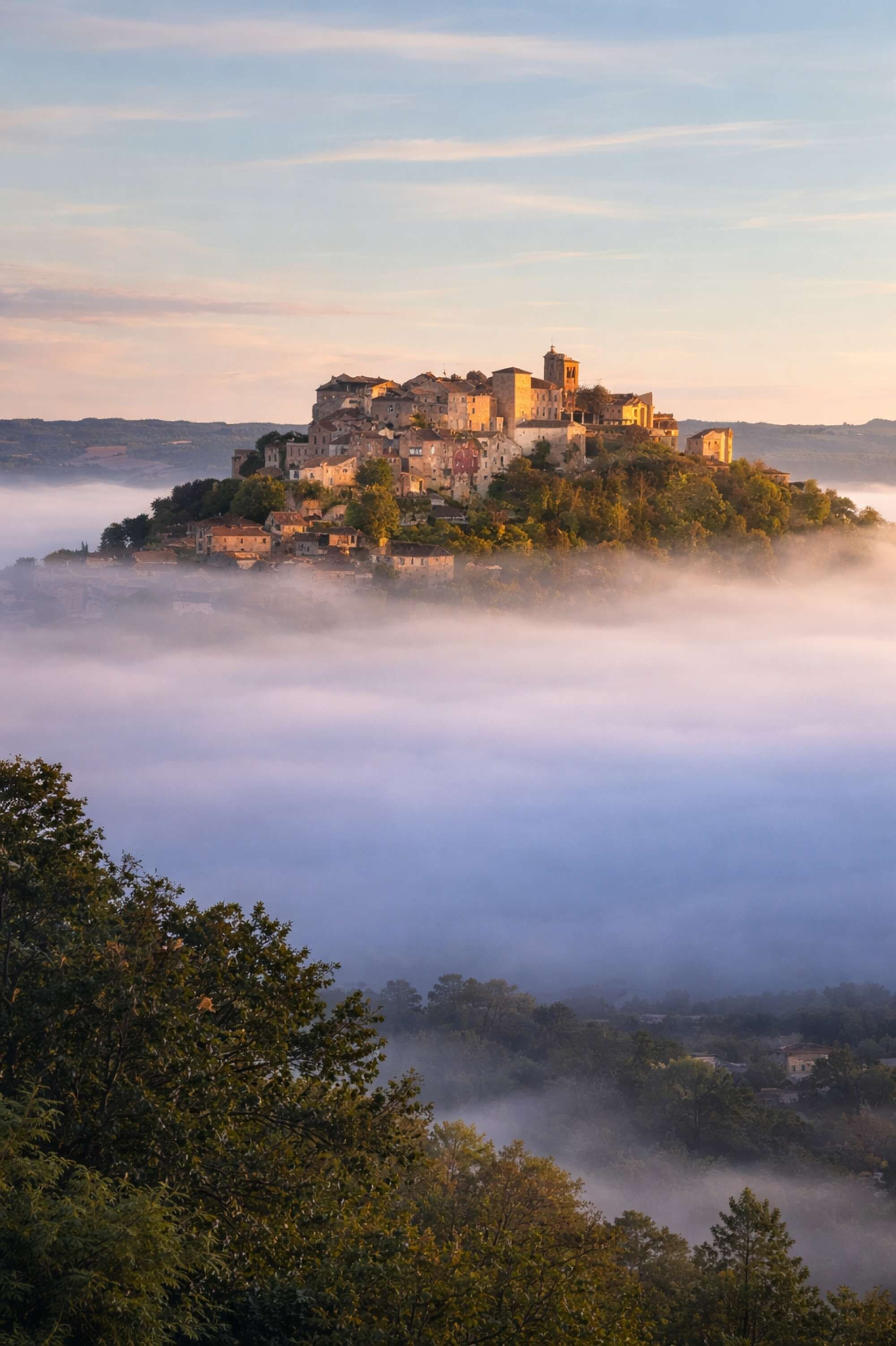 Un pueblo histórico enclavado en una colina, rodeado de niebla y vegetación.