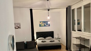 Ett modernt sovrum med en säng, en soffa, ett skrivbord och ett fönster.