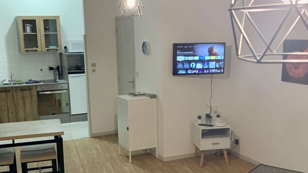 Ett modernt vardagsrum med kök, matplats och en tv som är monterad på väggen.