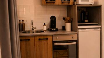 Cocina compacta con armarios de madera, microondas, cafetera y lavavajillas.