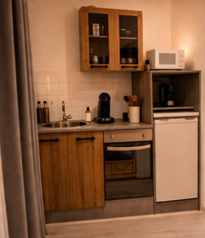 A compact kitchen with wooden cabinets, a microwave, a coffee maker, and a dishwasher.