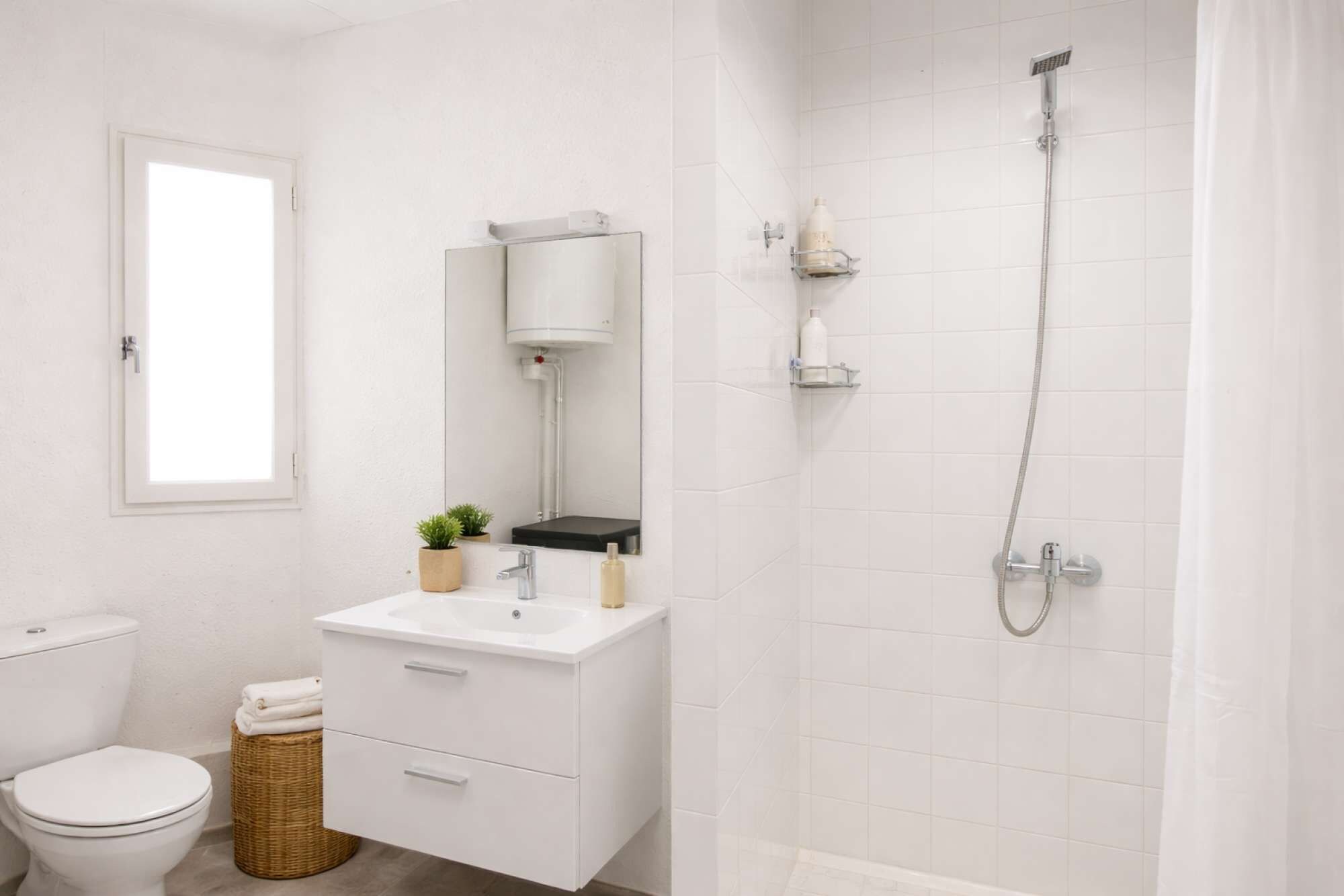 Une salle de bain équipée de toilettes, d’un lavabo, d’un miroir et d’une douche.