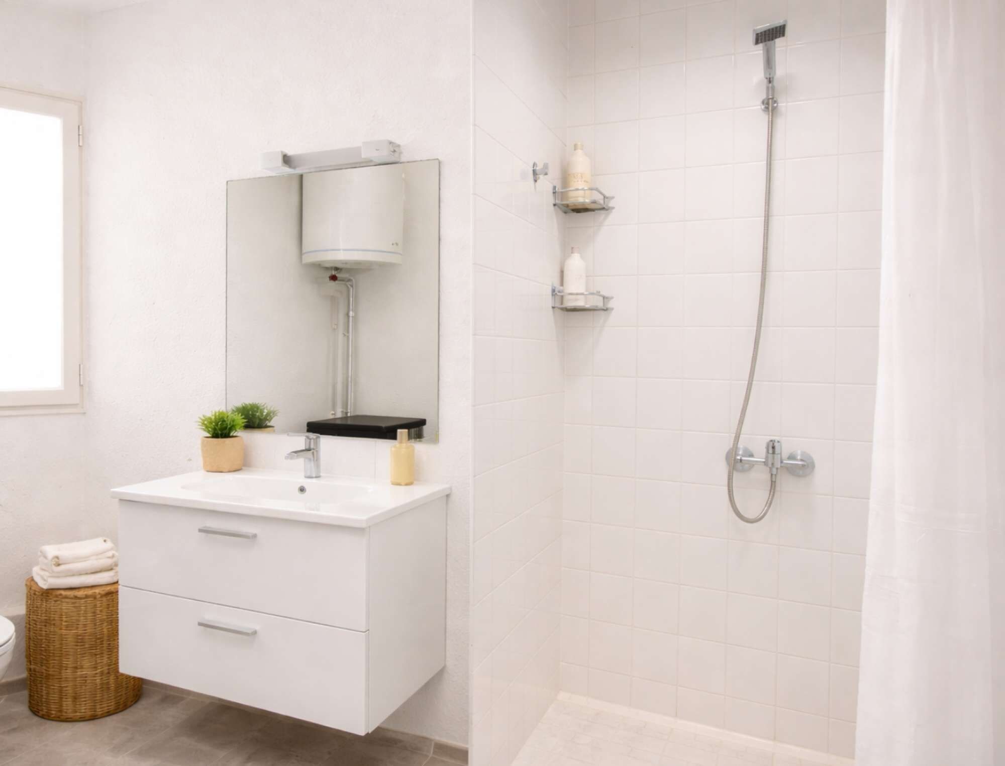 A bathroom with a white vanity, a mirror, a towel stack, and a shower area with a showerhead and control panel.