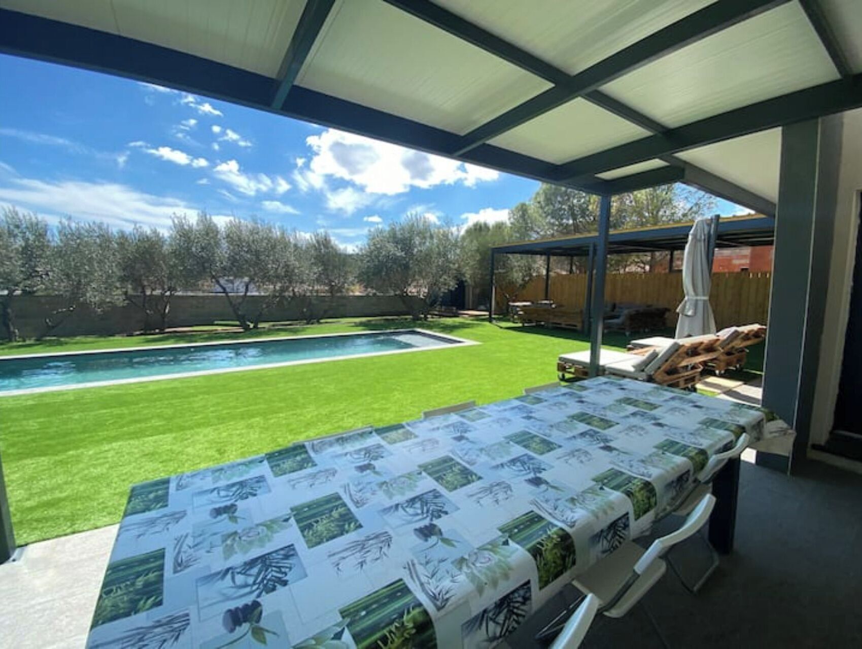 A covered patio area with a pool and lawn, featuring a table with printed images.