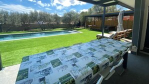 A covered patio area with a pool and lawn, featuring a table with printed images.