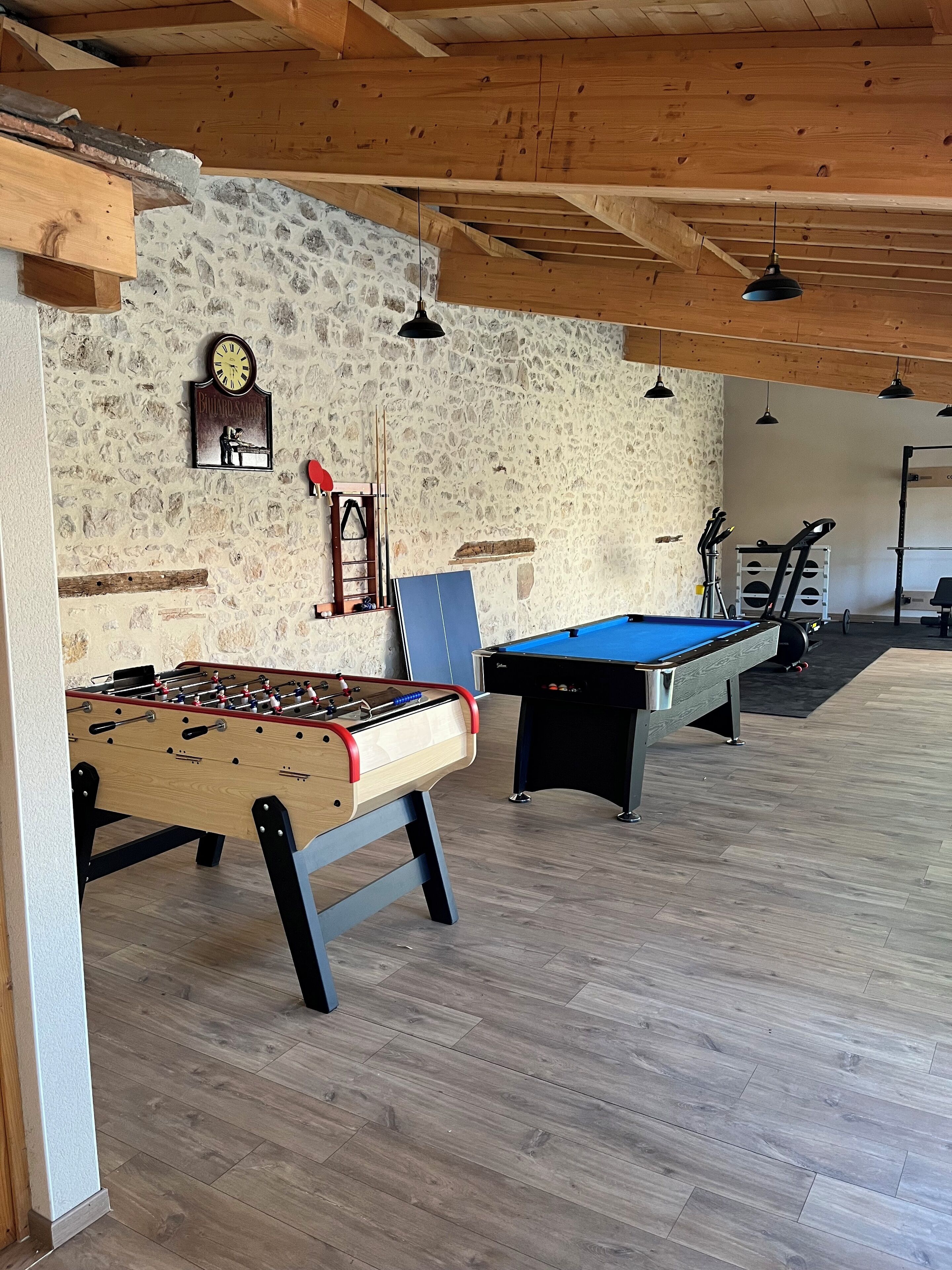 Ein Freizeitbereich mit Tischfußball, Billardtisch und Fitnessgeräten.
