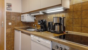 Ett kök med diskmaskin, mikrovågsugn, kaffebryggare och spis.