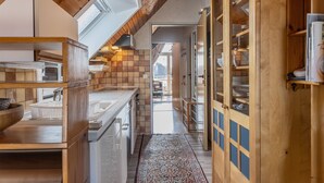 A modern kitchen with wooden cabinetry, a built-in oven, and a large window. - The simply furnished apartment Am Seestern Carolinensiel awaits you (Carolinensiel)