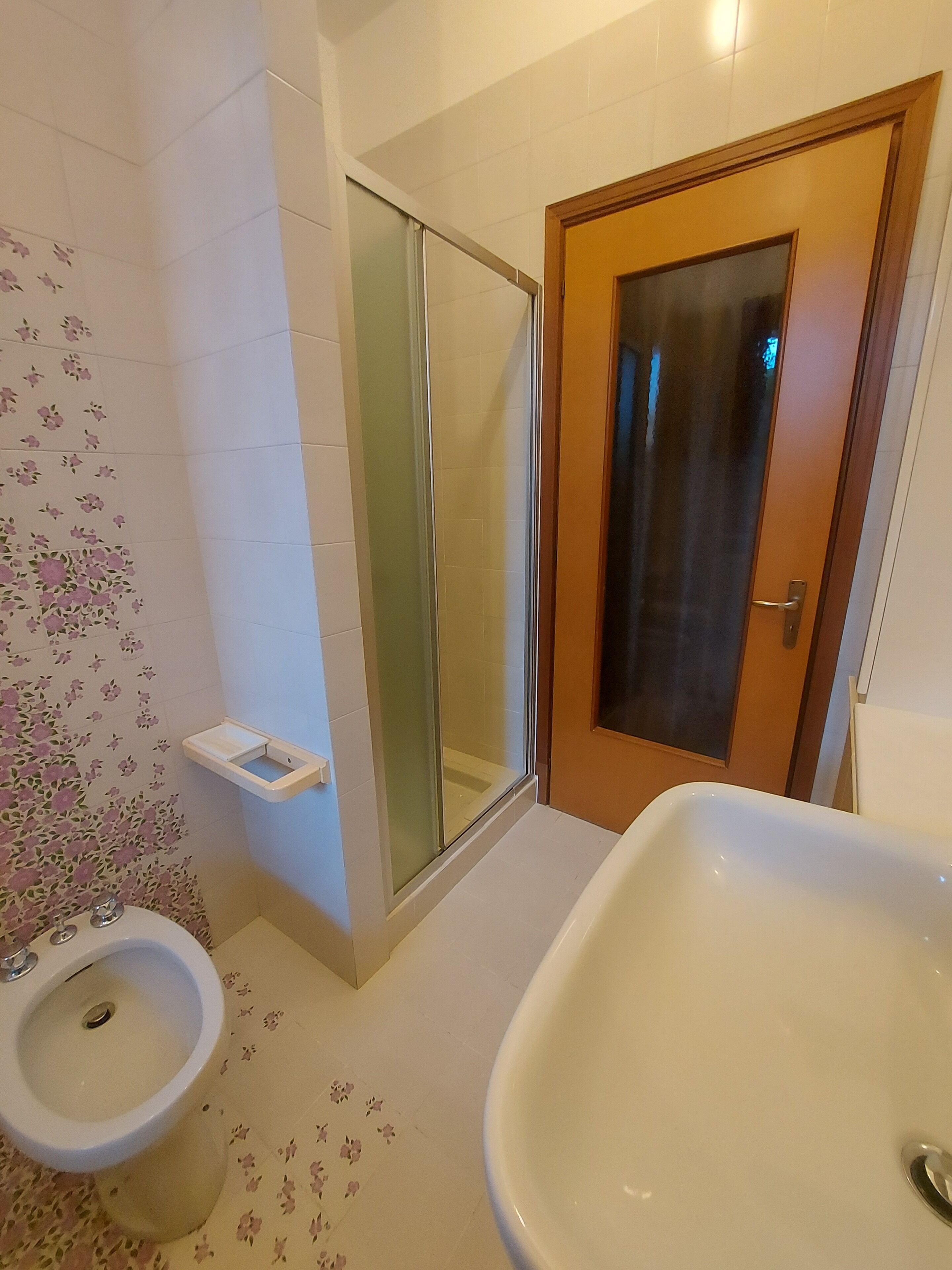 Un baño con inodoro, ducha con puerta de vidrio y lavamanos.