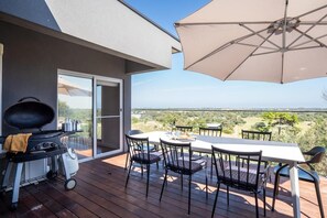 Enjoy al fresco dining and socializing on this outdoor patio with a grill, table, and comfortable seating.