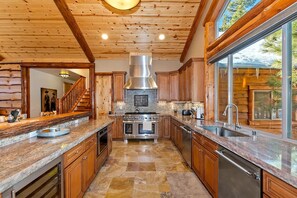 A spacious kitchen with a central island, wooden cabinets, and a large window providing a view of the outdoors.
