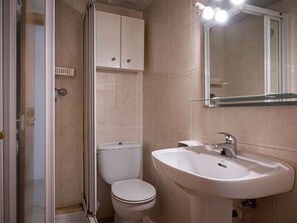 Ein Badezimmer mit Toilette, Waschbecken, Schrank und Spiegel.