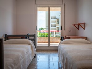 Ein Hotelzimmer mit zwei Betten, einem Balkon mit Blick auf Gebäude und einer Holzablage.