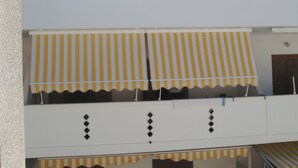 Un immeuble dont les balcons sont surmontés d’auvents à rayures jaunes et blanches.