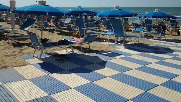 Une plage avec des parasols bleus et des chaises longues.