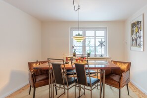 Un coin repas avec une table en bois, six chaises et un luminaire suspendu.