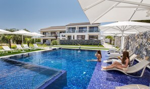 Relax by the pool surrounded by lounge chairs and umbrellas.