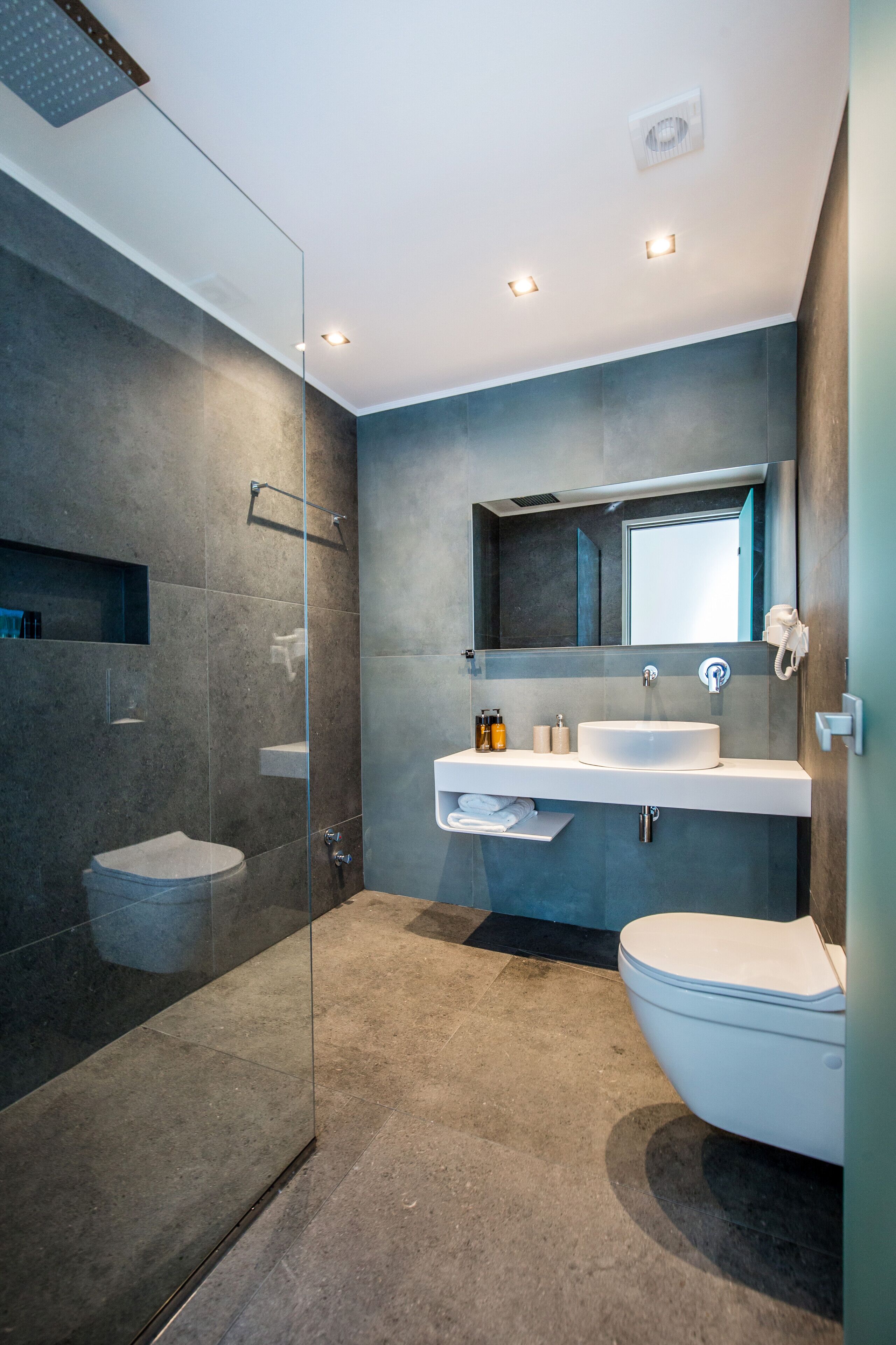 Een moderne badkamer met een douchecabine van glas, een witte wastafel en een toilet.