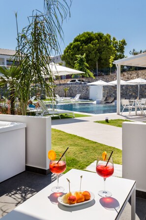 Relax by the pool with lounge chairs and umbrellas, surrounded by a well-manicured lawn and a shaded area.