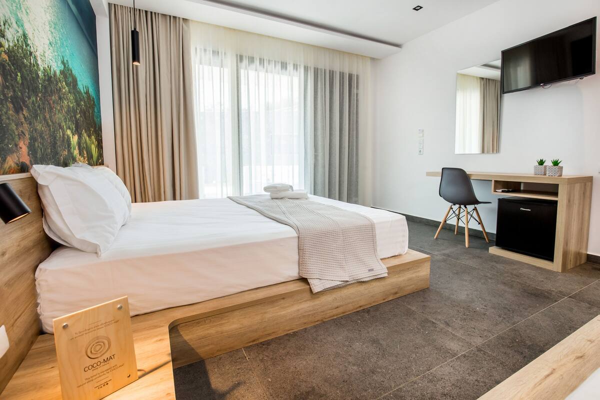 Quarto de hotel moderno com cama, escrivaninha e televisão.