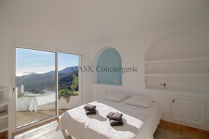 A bedroom with a bed, a view of the outdoors, and a sliding glass door. - VILLA L'ORANGER (La Croix-Valmer)