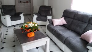 A living room with two grey sofas, a white coffee table, and a potted plant. - NANOU residence (Mont-Dore)